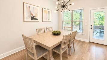A dining room with a wooden table, six chairs, and a chandelier.