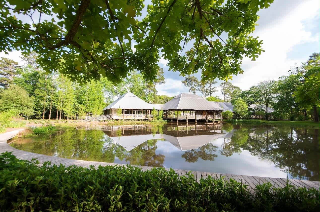 A lakeside building with a wooden deck and a reflection in the water.