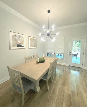 A dining room with a wooden table, six chairs, a chandelier, and two framed artworks on the wall. - Tigers Geaux Crazy at The Wild LSU Jungle - KC7049 (Baton Rouge)