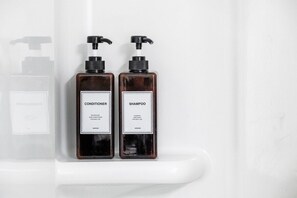 Zwei Flaschen Conditioner und Shampoo auf einem weißen Regal.