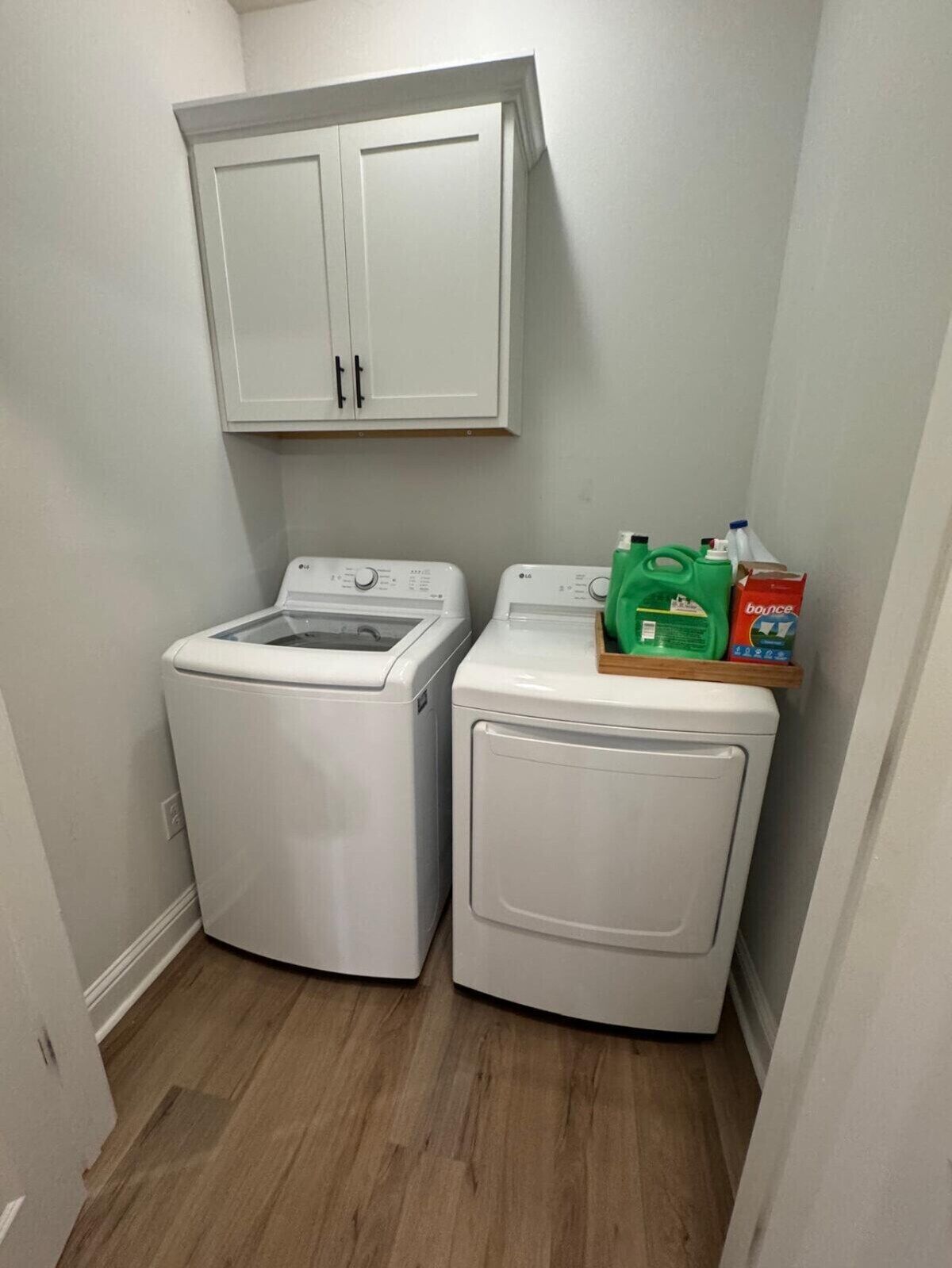 A laundry room with two white front-loading washing machines and a cabinet above them.