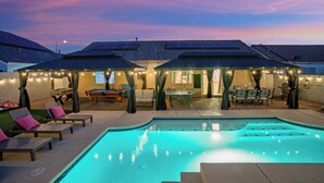 A swimming pool with lounge chairs and a covered patio area. - Spectacular 5BR Home: Pool and Relaxing Space! (North Las Vegas)