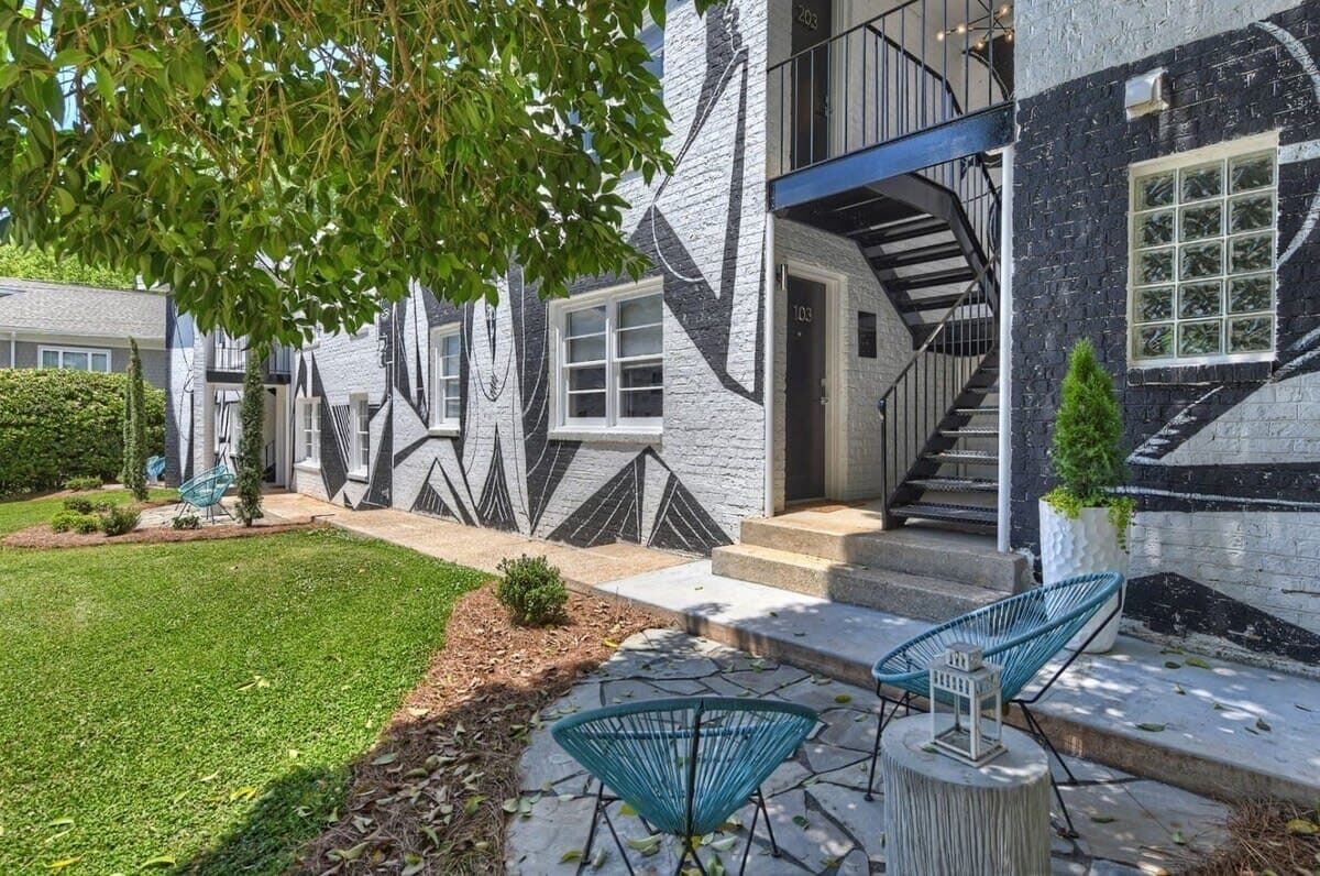 A modern building with a geometric facade, a staircase leading to the entrance, and outdoor seating.