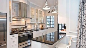 A modern kitchen with a central island, stainless steel appliances, and pendant lighting.