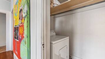 A laundry area with a washing machine and a shelf above it.