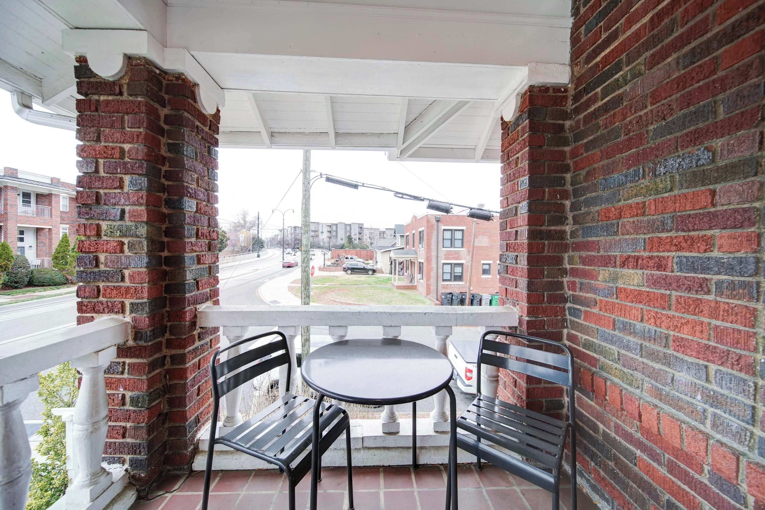A balcony with a brick wall, a table, and two chairs.