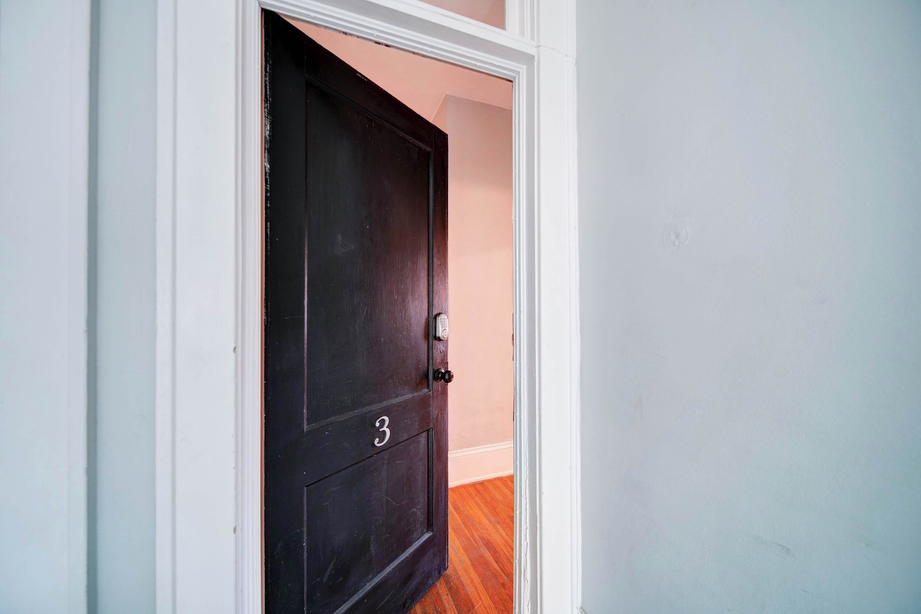 A dark wooden door with the number 3, white trim, and a keyhole.