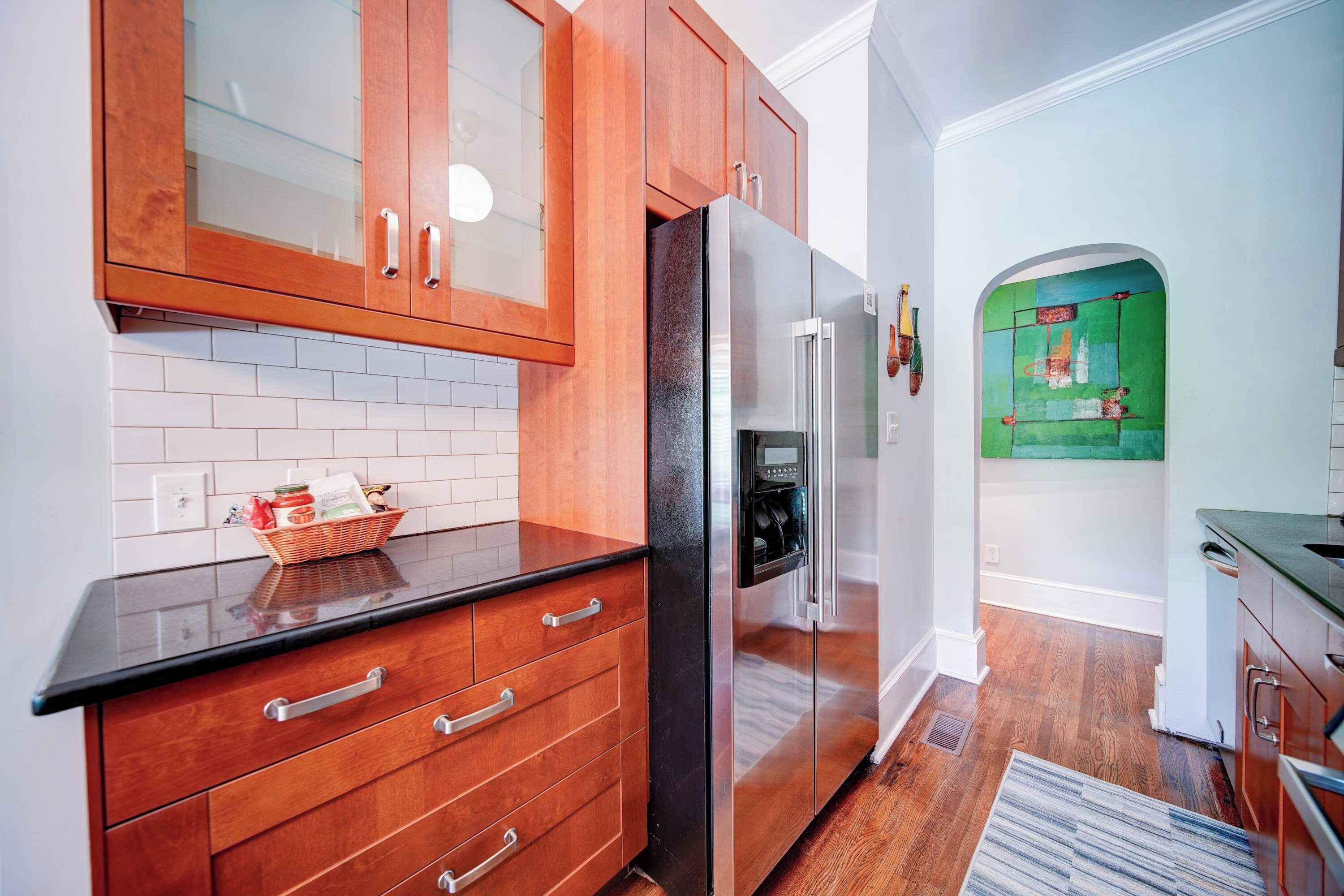 Una cocina moderna con armarios de madera, un refrigerador negro y un salpicadero de azulejos.