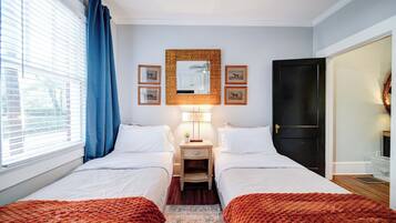 Een hotelkamer met twee bedden, een nachtkastje met een lamp, een spiegel en beeldeijkjes aan de muur.