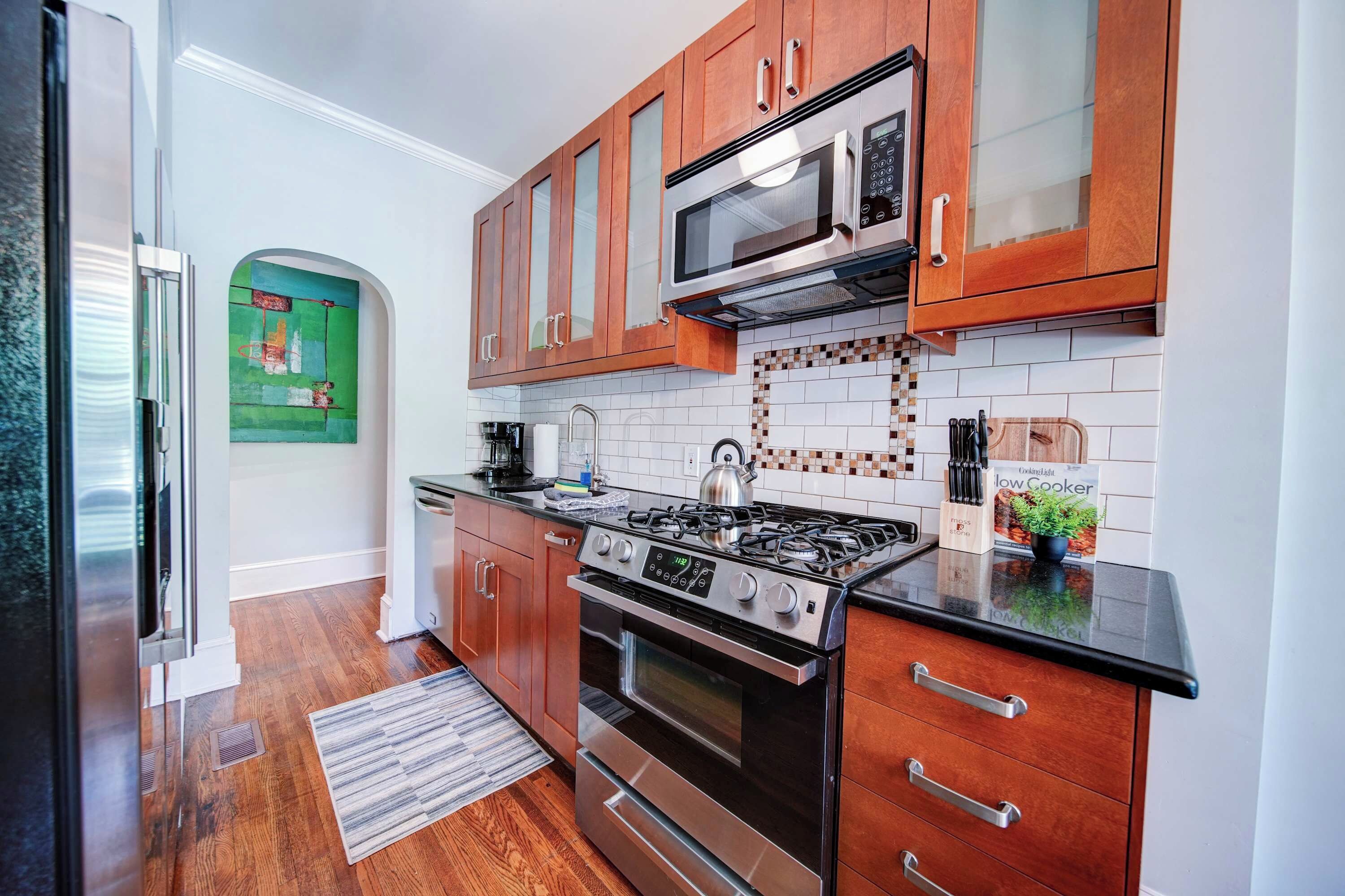 A modern kitchen with wooden cabinets, a stainless steel stove, and a microwave.