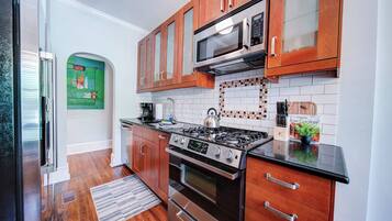A modern kitchen with wooden cabinets, a stainless steel stove, and a microwave.