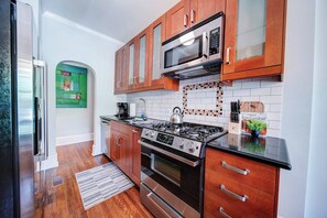 Una cocina moderna con armarios de madera, estufa de acero inoxidable y microondas.