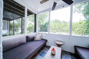 Un solárium con una zona de estar acolchada, una mesita y vistas al exterior con vegetación.