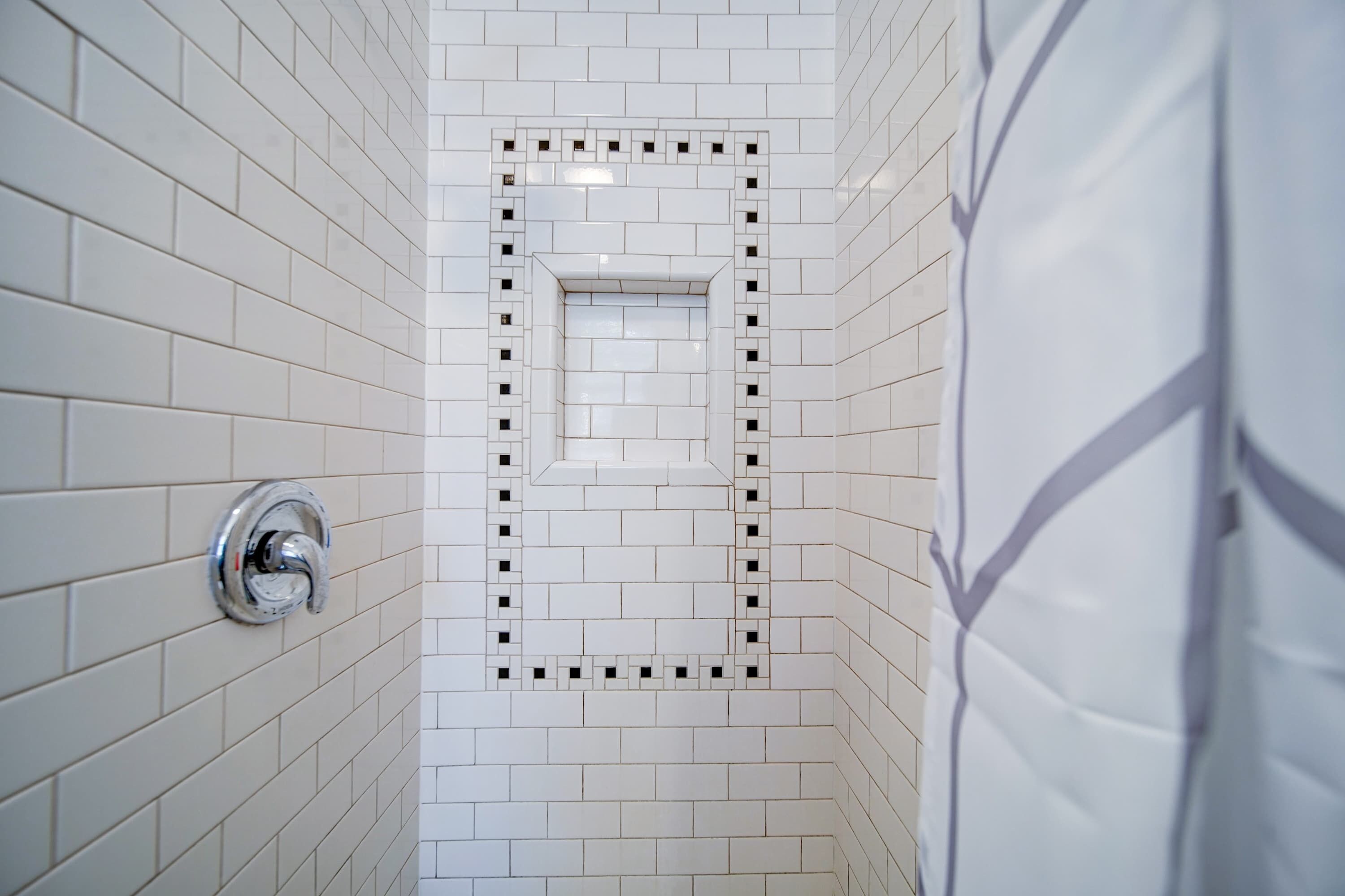 Een badkamer met witte betegelde wanden en een douchehoek.