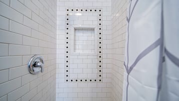 Een badkamer met witte betegelde wanden en een douchehoek.