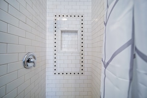 Ein Badezimmer mit weiß gefliesten Wänden und einer Duschkabine.