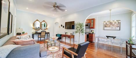 A spacious living room with a sofa, coffee table, and dining area with chairs.