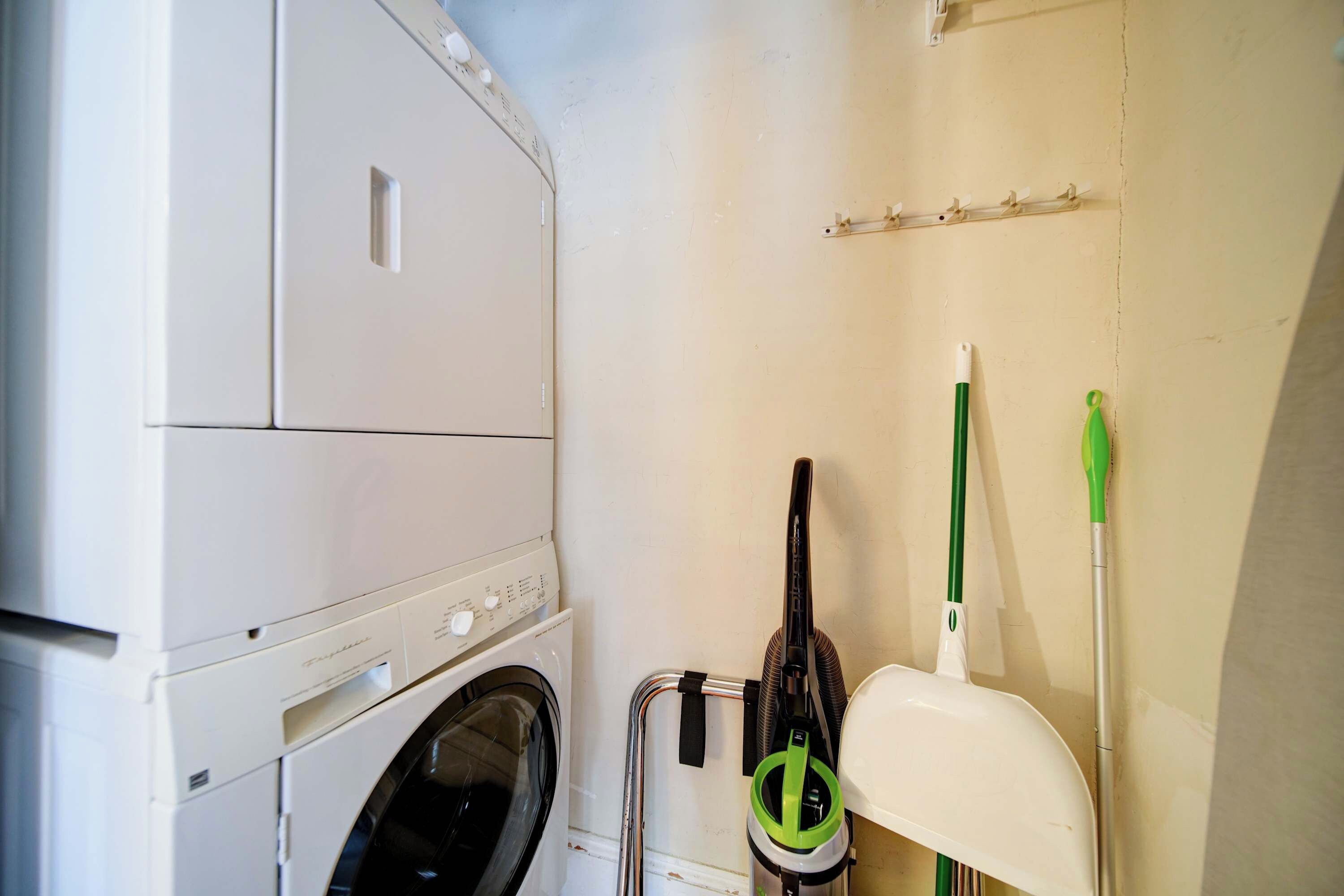 A laundry area with a washing machine, a drying rack, and a mop.