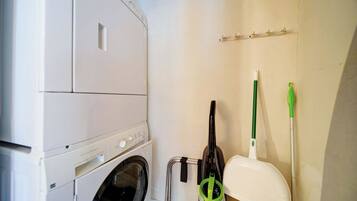 A laundry area with a washing machine, a drying rack, and a mop.