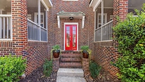 A brick building with a red door, numbered 2101, and a small porch with steps leading to the entrance. - Historic Dilworth 1BR Apartment: King Suite Near Atrium Health & Uptown (Charlotte)