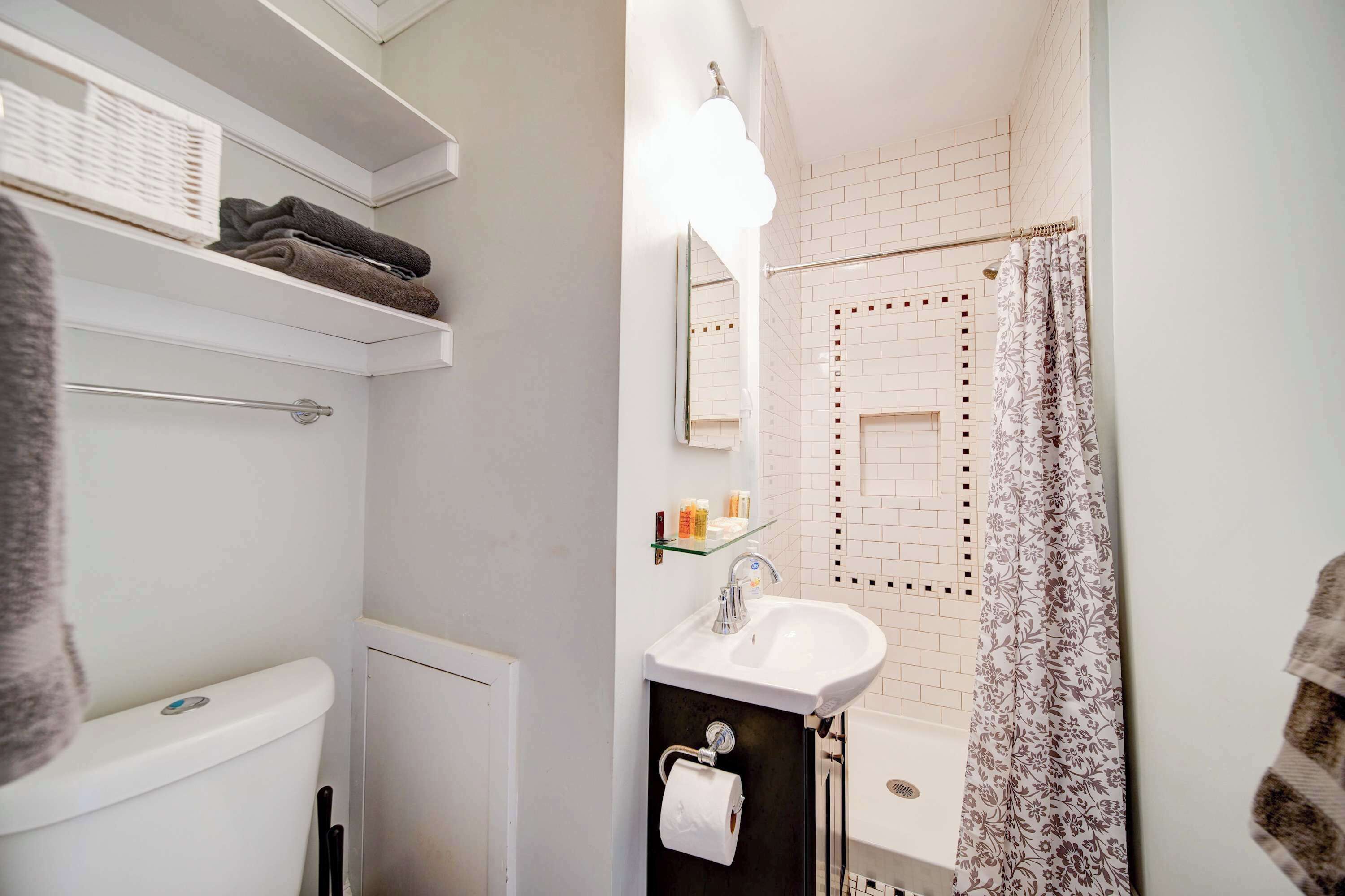 A bathroom with a toilet, sink, mirror, towel rack, and shower curtain.