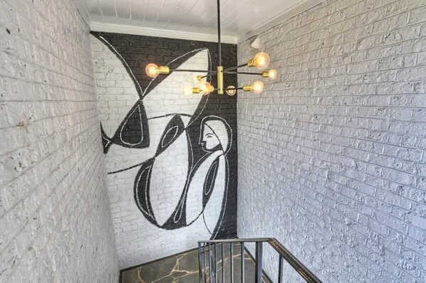 Een trap met een moderne lamp en een groot abstract schilderij op de muur.