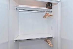Een witte kast met een metalen stang en houten kledinghangers.