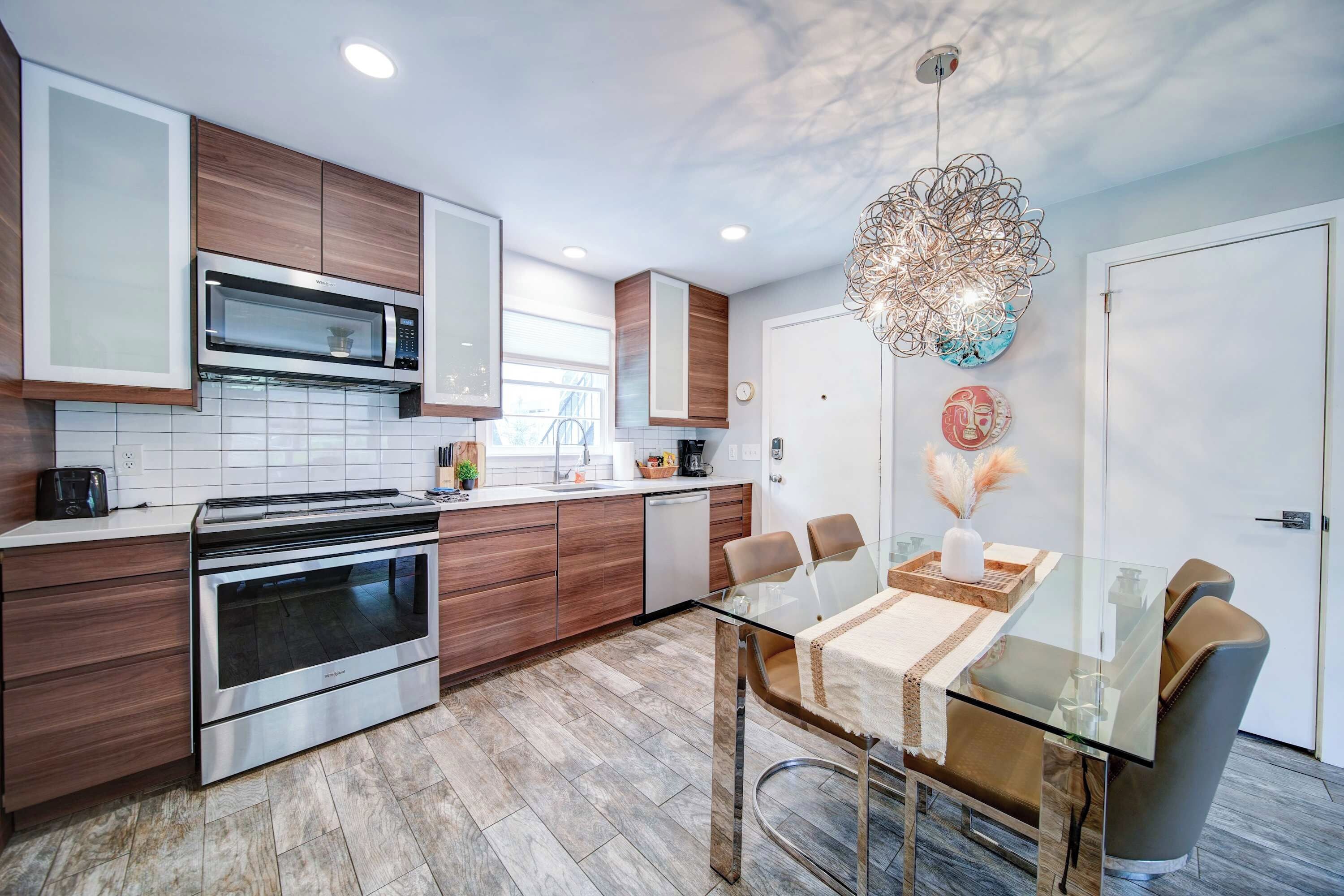 A modern kitchen with stainless steel appliances, wooden cabinets, and a glass dining table with chairs.