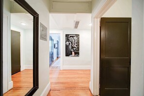 A hallway with wooden flooring, a dark door, and a wall-mounted artwork.