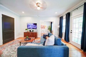 A living room with a blue sofa, a coffee table, and a flat-screen TV.