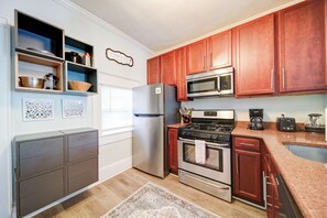 Una cocina moderna con electrodomésticos de acero inoxidable, armarios de madera y decoración en la pared.