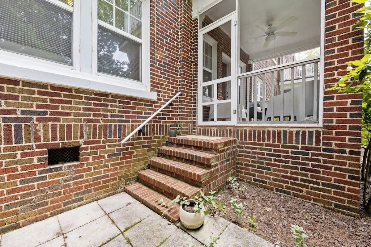 A brick exterior with a set of outdoor stairs leading to a covered porch area.
