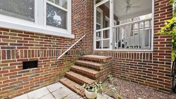 A brick exterior with a set of outdoor stairs leading to a covered porch area.