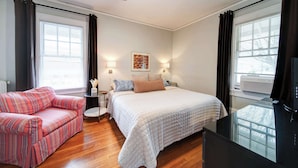 A bedroom with a bed, a sofa, a TV, and a ceiling fan. - The Home Collection: Hawthorne 1BR King Suite | Private Balcony | Walk to Novant (Charlotte)