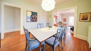 A dining area with a white table, blue chairs, and a decorative light fixture. - The Home Collection: Hawthorne 1BR King Suite | Private Balcony | Walk to Novant (Charlotte)