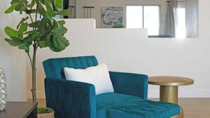 A teal armchair with a white pillow, a small round table with a gold base, and a potted plant. - Stunning 5BD Escape w/ Billiard Room & Pool! (North Las Vegas)