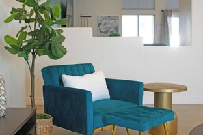A teal armchair with a white pillow, a small round table with a gold base, and a potted plant. - Stunning 5BD Escape w/ Billiard Room & Pool! (North Las Vegas)