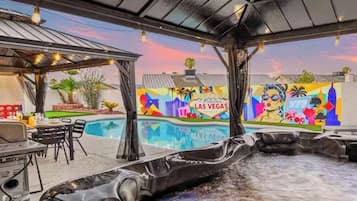 A hot tub area with a pool, outdoor seating, and a mural with 'Las Vegas' text.