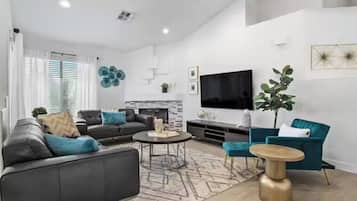 A modern living room with a sofa, coffee table, and a TV mounted on the wall.
