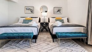 A hotel room with two beds, a round mirror, and a small table between them. - Stunning 5BD Escape w/ Billiard Room & Pool! (North Las Vegas)