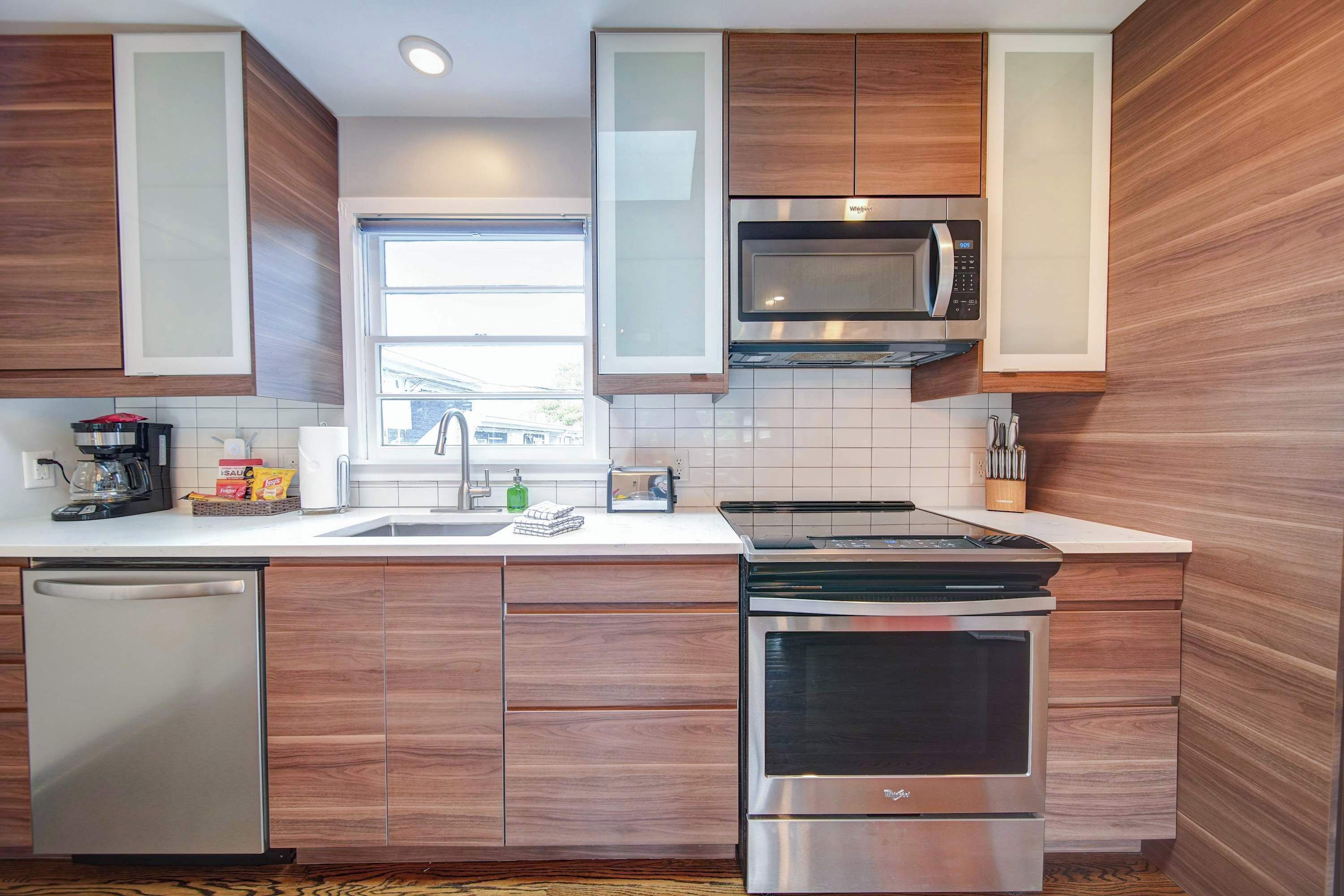 A modern kitchen with wooden cabinets, a microwave, a dishwasher, and a stove.