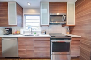 Una cocina moderna con armarios de madera, microondas, lavavajillas y estufa.