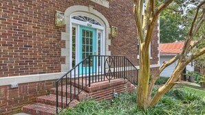 A brick building with a turquoise door, numbered 518, and a black metal staircase leading to the entrance.