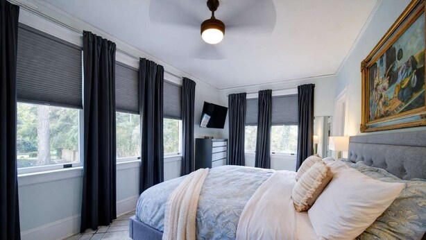 A bedroom with a bed, a television on a stand, and a painting on the wall.