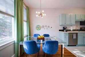 Una cocina moderna con armarios azul claro, una mesa de comedor de vidrio y sillas azules, y un candelabro.