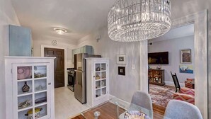 A modern kitchen with white cabinetry, a stainless steel refrigerator, and a chandelier.