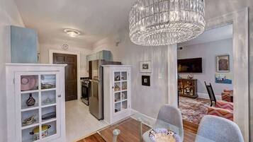 A modern kitchen with white cabinetry, a stainless steel refrigerator, and a chandelier.