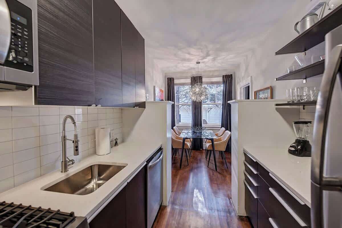 A modern kitchen with a central island, stainless steel appliances, and a view to the outside.