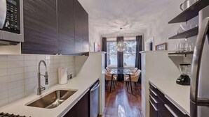 A modern kitchen with a central island, stainless steel appliances, and a view to the outside.