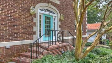 A brick building with a turquoise door and a black metal staircase leading to the entrance.